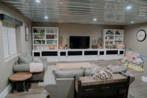 Cozy gray-toned living room with built-ins, TV, and play area in Riddle Road farmhouse